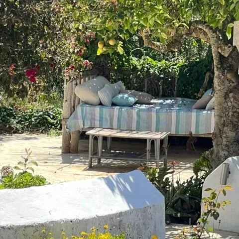 A cozy outdoor daybed with striped linens and blue pillows