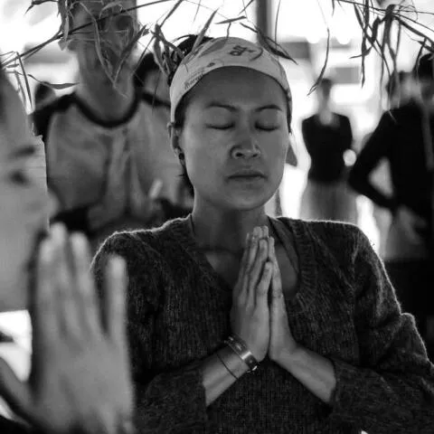 A group of people sitting in a circle on yoga mats in a studio