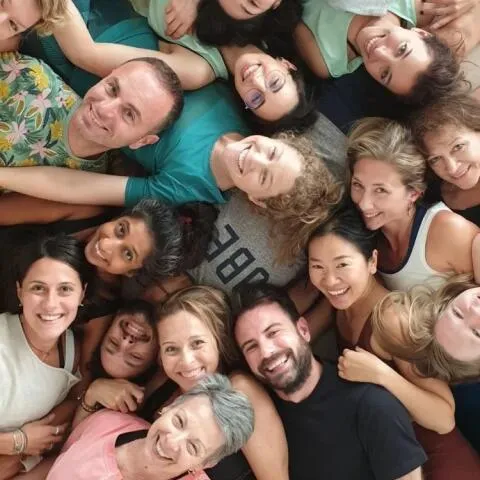 A top-down, circular group photo of smiling people lying on the floor