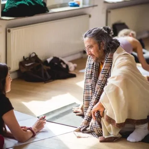 A male yoga instructor engaged in a focused conversation with a student