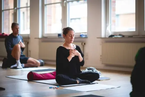 A woman sitting on a yoga mat and praying