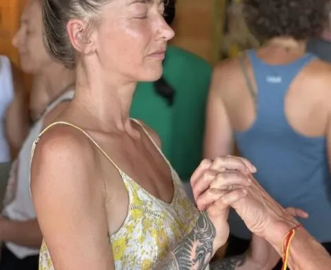 A group of people practicing a seated twist yoga pose in a bright studio
