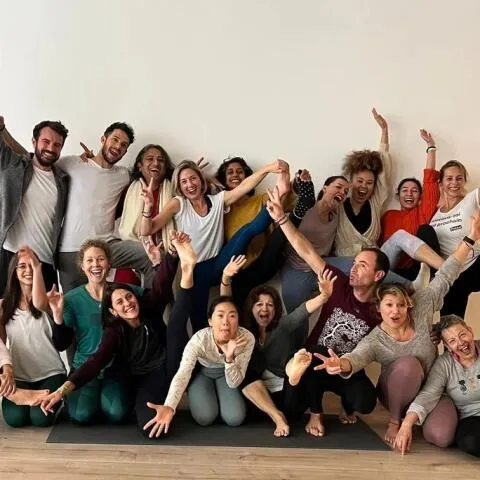 A large, diverse group of yoga practitioners posing playfully