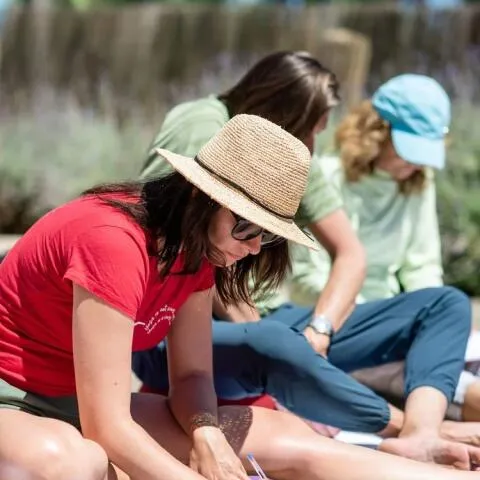 A woman in a red t-shirt and straw hat sitting outdoors