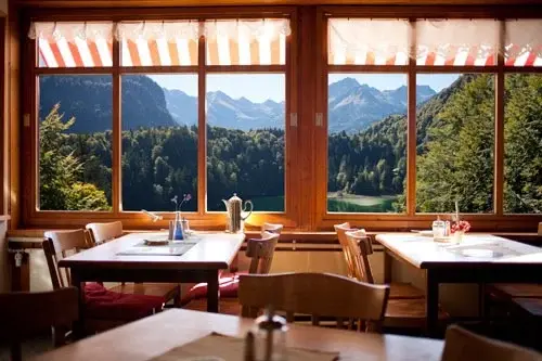 Cozy dining room with wooden tables and a large window looking out onto mountain peaks.