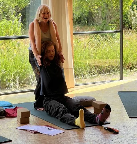 Instructor assisting seated yoga stretch