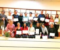 Yoga teacher training graduates holding certificates.